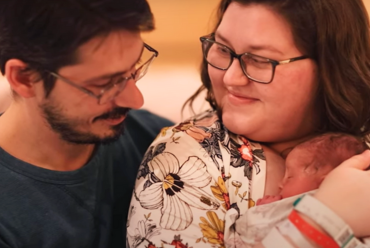 A mother and father lovingly hold their newborn baby in a hospital setting, sharing a warm and emotional moment together.