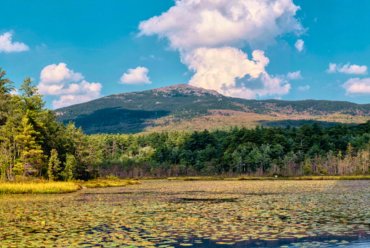 A scenic view of Mount Monadnock in New Hampshire, with a peaceful lake and surrounding forest.