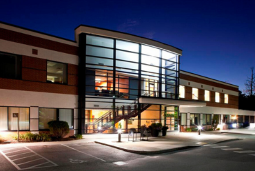 A modern photo of the Bond Wellness Center building at night, with bright lights and a sleek design.