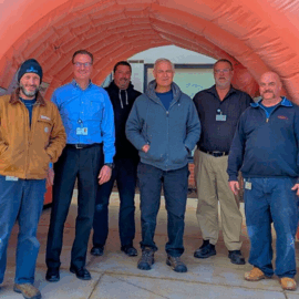 Monadnock Community Hospital engineering team members pose smiling inside a large inflatable colon used for health education.