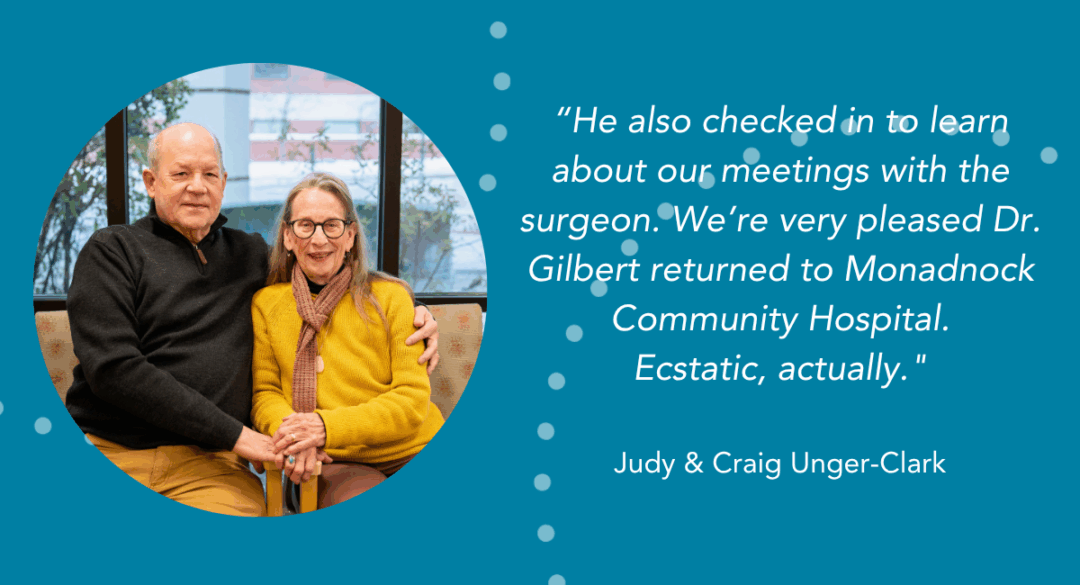 Judy and Craig Unger-Clark sit close together and smile in a waiting area with large windows and soft natural light behind them.