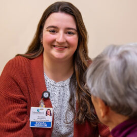A social worker smiles while meeting with a patient in a private room.