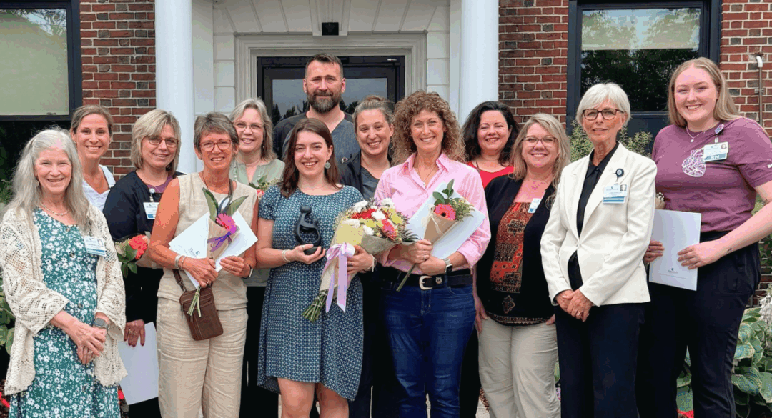 Group of nurses and hospital staff gathered outside Monadnock Community Hospital to celebrate the 2025 DAISY Award Ceremony, with Zoe Crowley holding flowers and an award at the center.