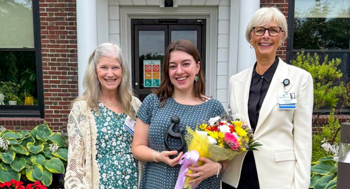 Zoe Crowley, center, holds a bouquet of flowers and The Healer’s Touch sculpture while standing with Cyndee McGuire President & CEO (right) and Vicki Campanile Chief Nursing Officer (left) in front of Monadnock Community Hospital.