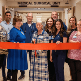 Monadnock Community Hospital staff and leadership gathered in front of the Medical-Surgical Unit holding a red ribbon at a ribbon-cutting ceremony to celebrate the unit’s renovation.
