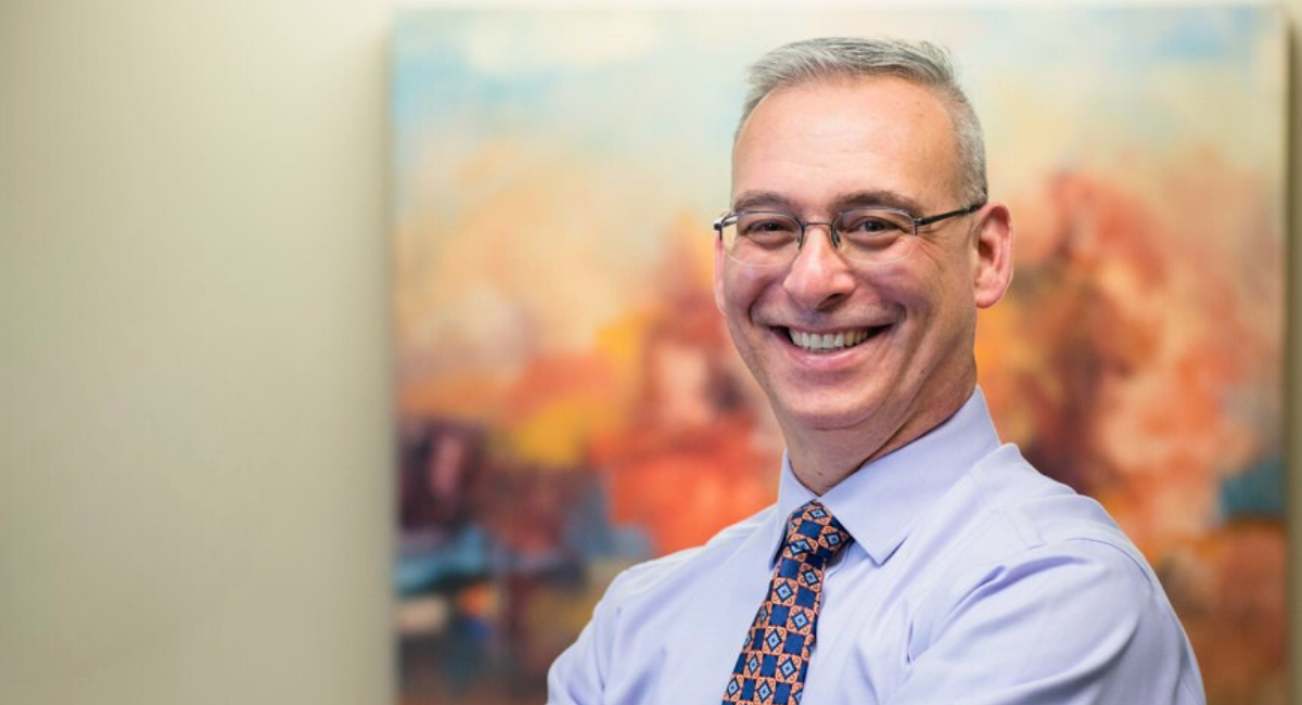 Rich Scheinblum Chief Financial Officer at Monadnock Community Hospital smiling in front of a colorful painting