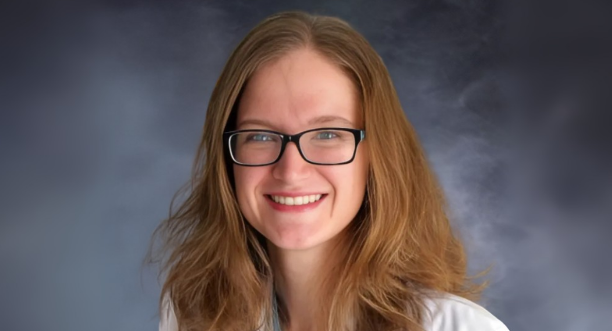 Professional headshot of Morgan Jenkins, MD, wearing glasses and a white coat, smiling against a soft dark gray studio background.