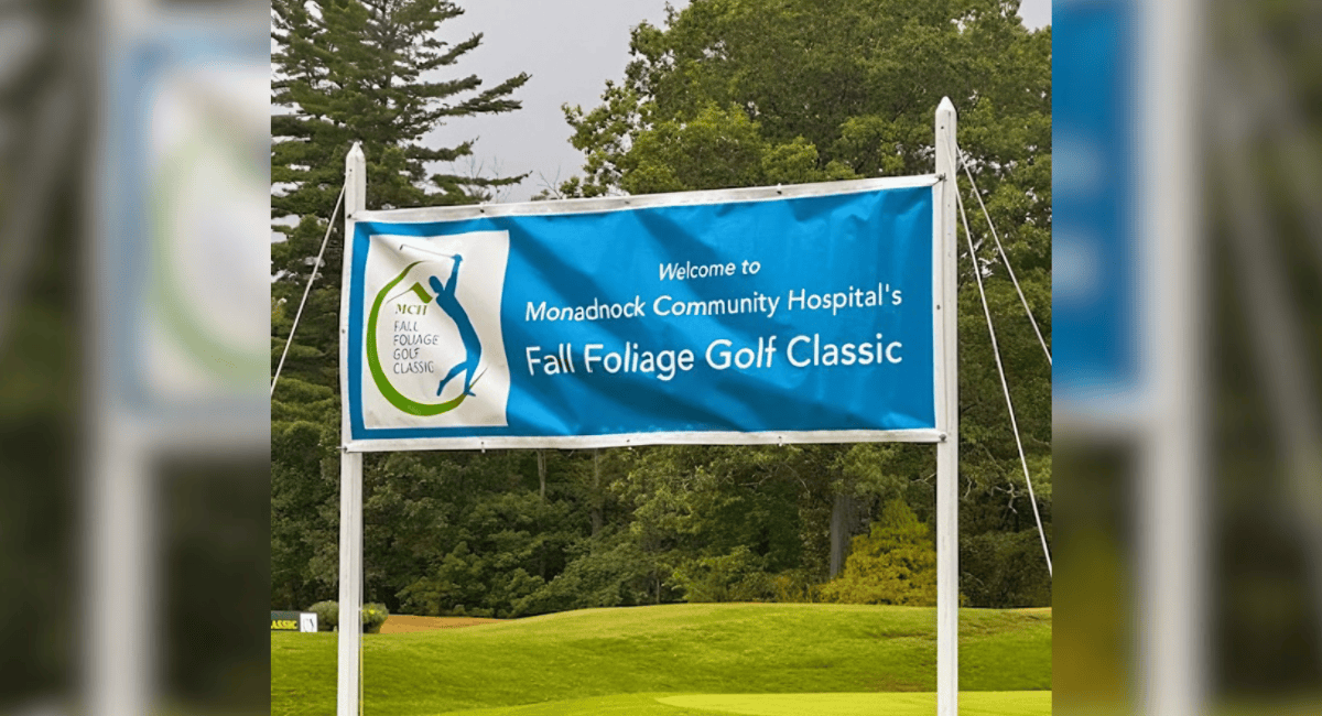 Outdoor banner on a golf course welcoming participants to Monadnock Community Hospital’s Fall Foliage Golf Classic, framed by potted flowers on the grass.