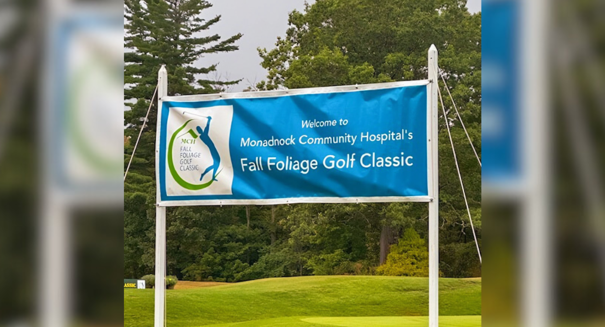 Outdoor banner on a golf course welcoming participants to Monadnock Community Hospital’s Fall Foliage Golf Classic, framed by potted flowers on the grass.