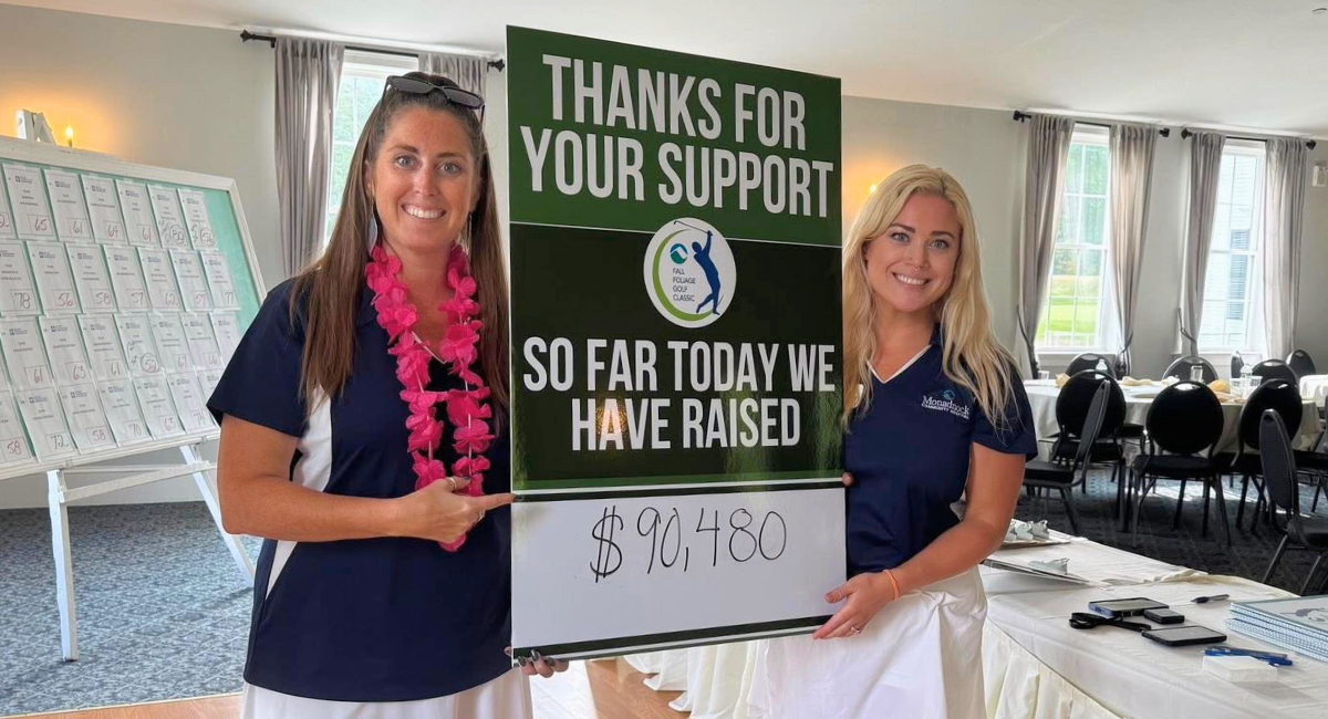 Two Monadnock Community Hospital staff smile while holding a large sign that reads, “Thanks for your support – So far today we have raised $90,480.”