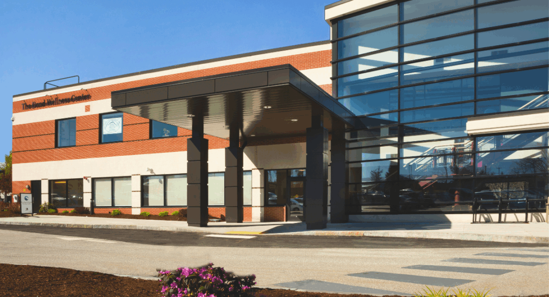 “Exterior of the Bond Wellness Center at Monadnock Community Hospital, featuring glass windows, brick walls, and a covered entrance