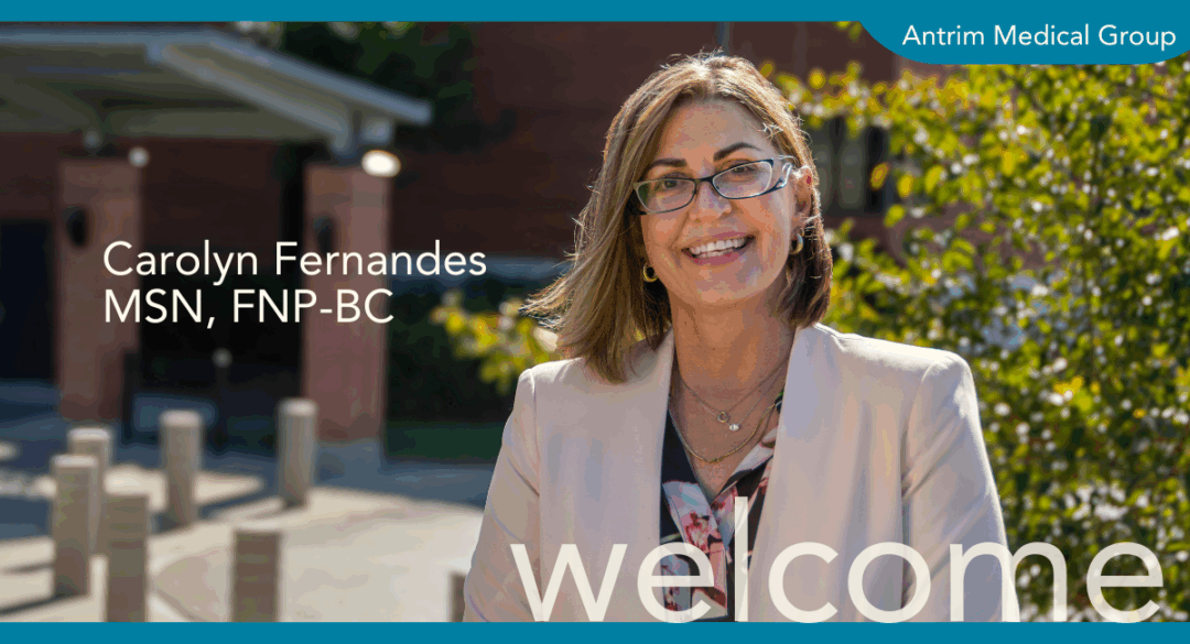 Professional photo of Carolyn Fernandes, MSN, FNP-BC, smiling outside Antrim Medical Group, with welcome text and clinic branding.