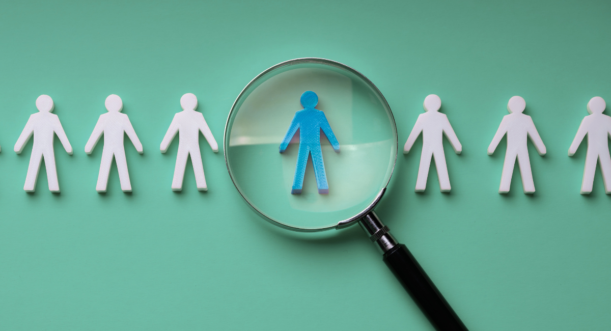 line of silhouettes of people with one in the center being blue