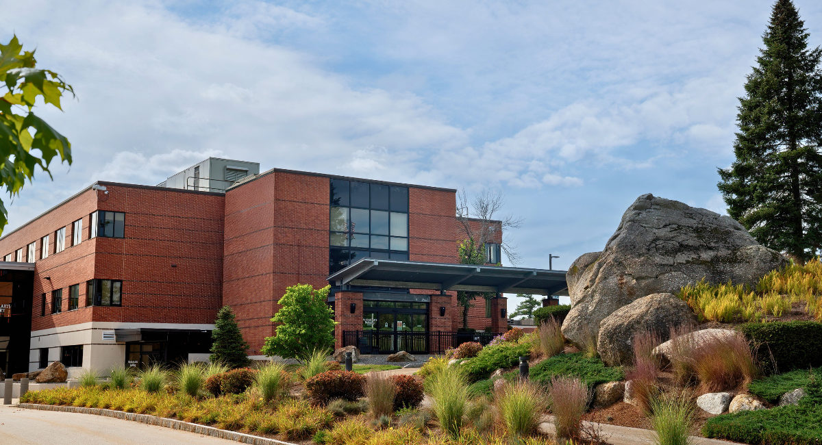 Monadnock Community Hospital in Peterborough, New Hampshire, with the red brick hospital building, landscaped gardens, and large granite boulders at the main entrance.