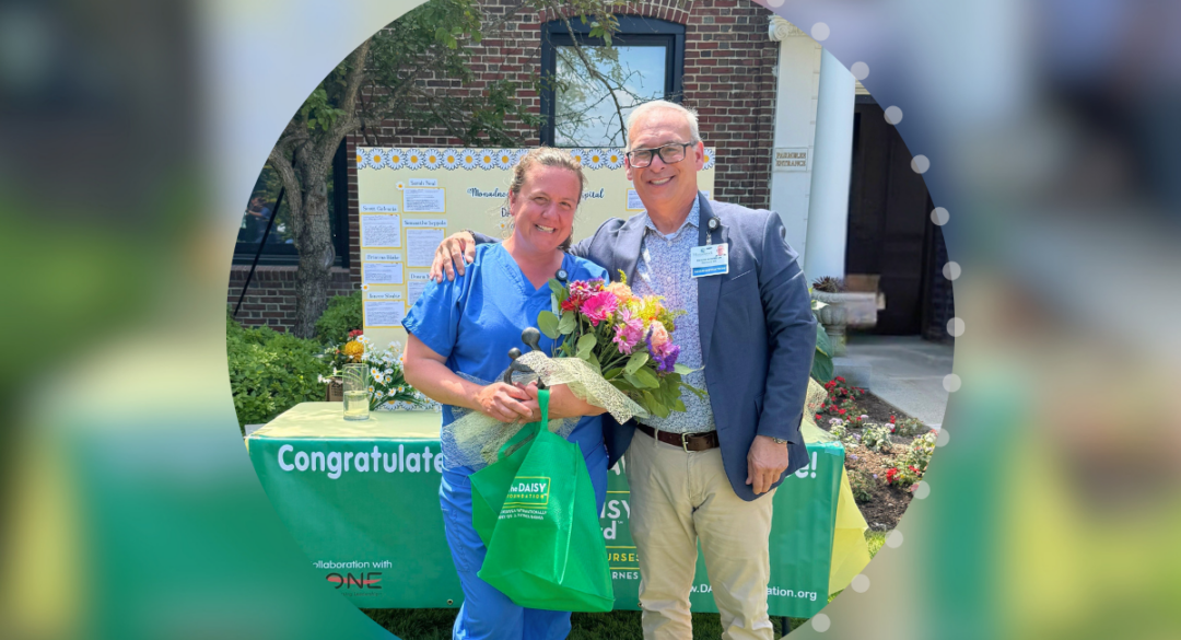 Beth LeClair, RN, of Monadnock Community Hospital's Birthing Suite, stands with President and CEO Richard Scheinblum after receiving the 2026 DAISY Award. LeClair holds flowers, the DAISY Healer's Touch sculpture, and award gifts during the outdoor recognition ceremony.