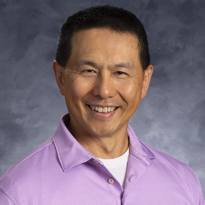 Headshot of Henry Lin, MD, smiling in a light purple button-down shirt against a gray-blue background.
